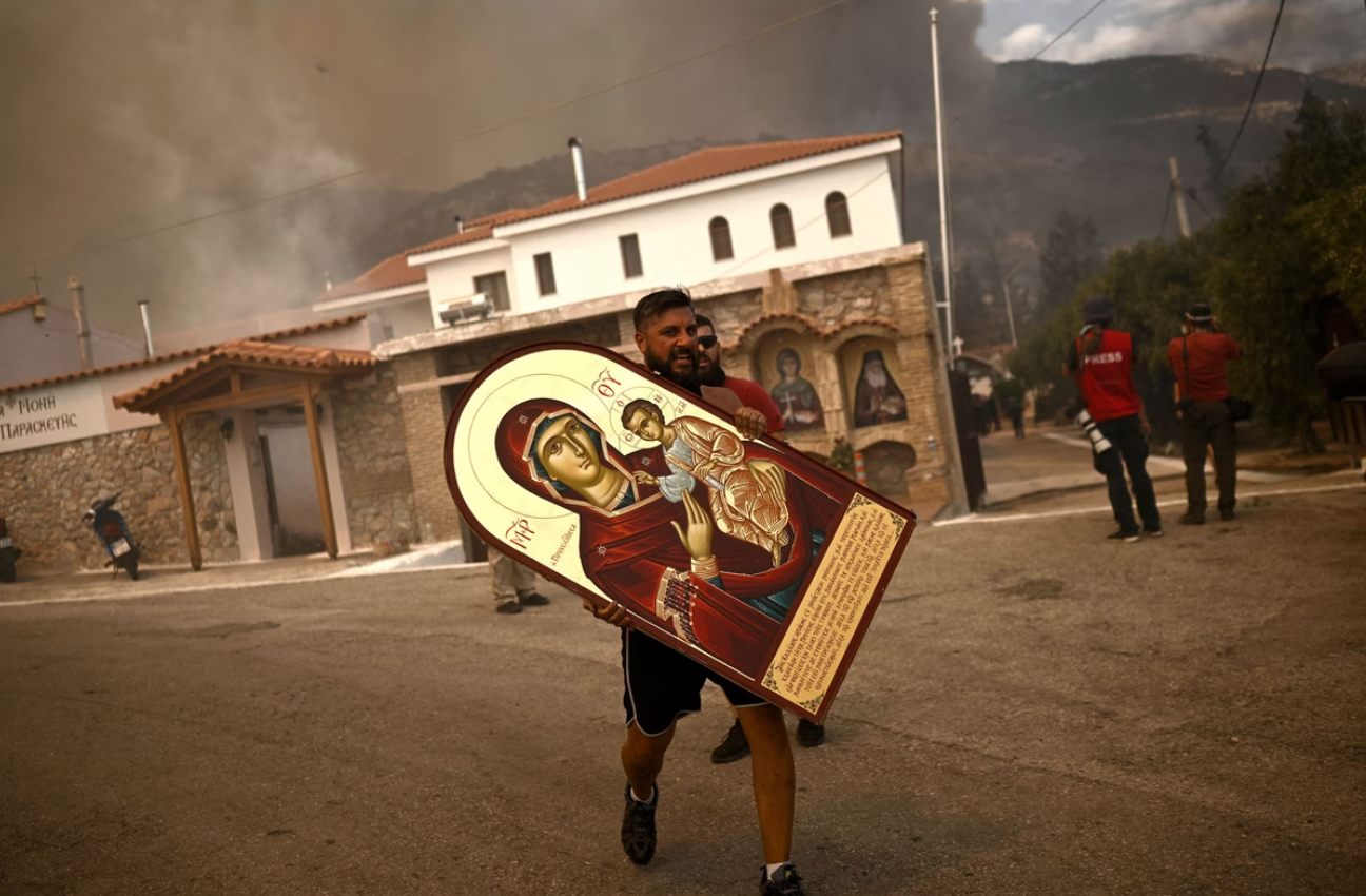 A volunteer carries an icon from a burning monastery as a wildfire spreads in Archanes, north of Athens, on August 23, 2023. #

Angelos Tzortzinis / AFP / Getty
